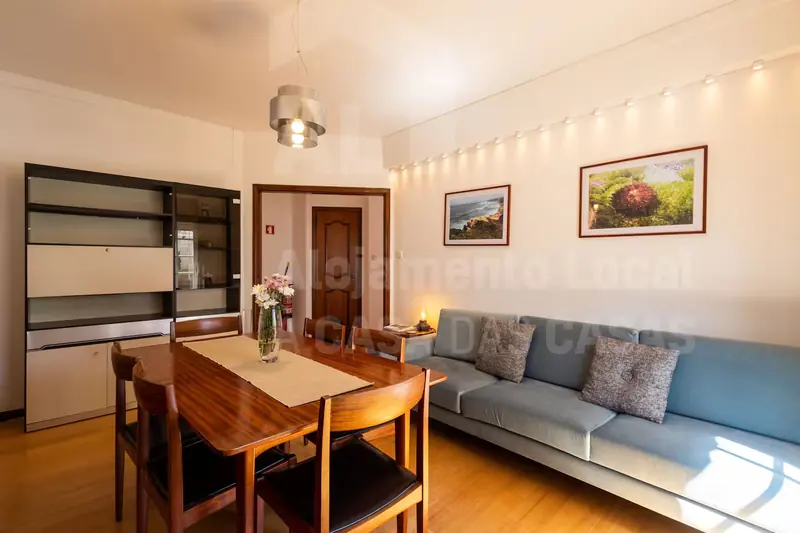 Sala com sofá azul, estante e mesa de jantar