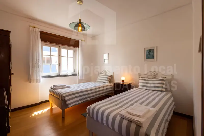 Quarto com duas camas individuais com colchas às riscas cinzentas
