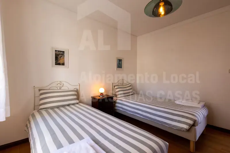Quarto com duas camas individuais e candeeiro de mesa