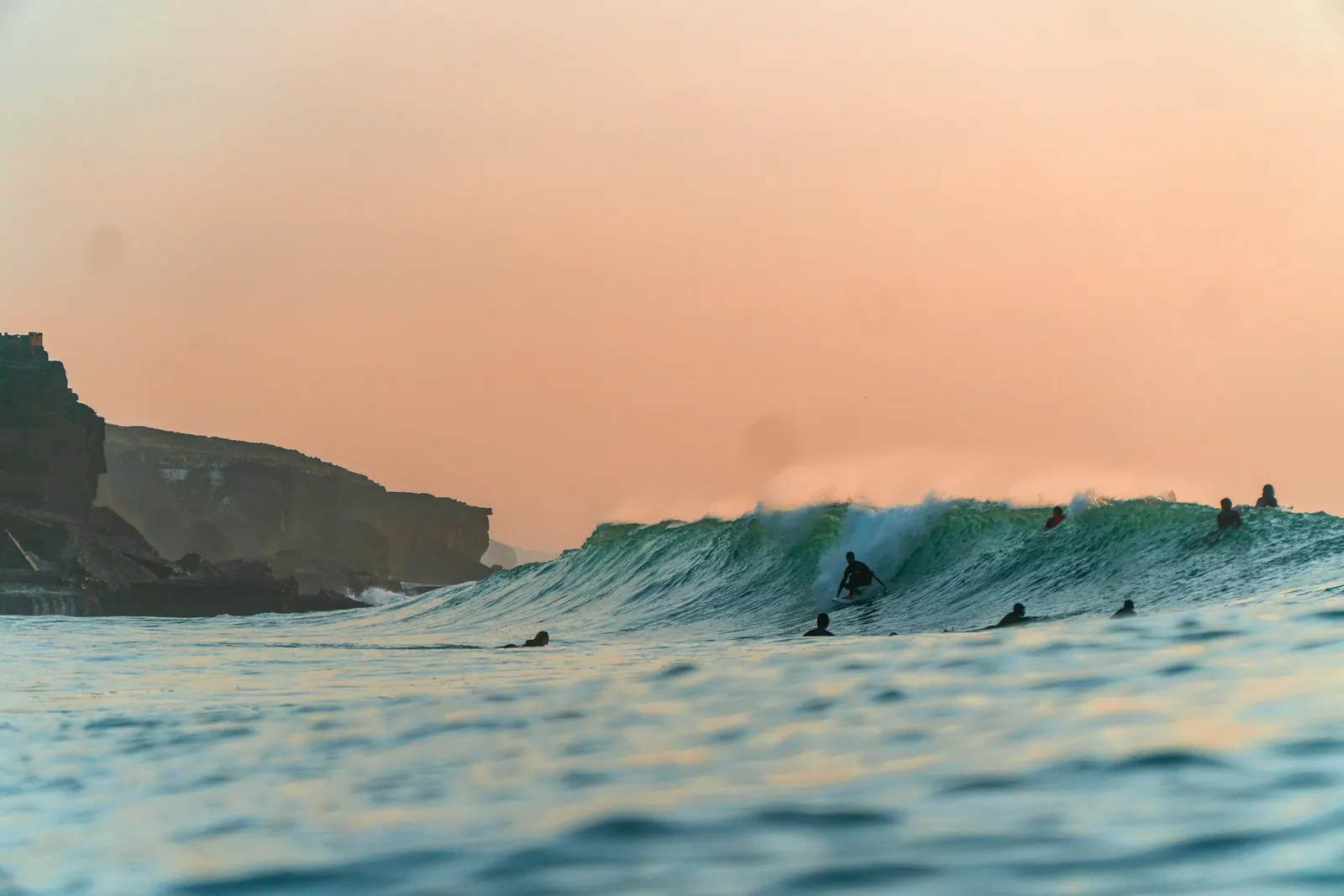 Surfistas numa onda junto às falésias ao fim da tarde